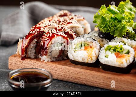 Nahaufnahme auf Sushi-Rolle sortiert auf dem Holzbrett Mit Sojasauce Stockfoto