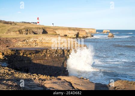 Wellen brechen über Klippen südlich von Souter Point, in Whitburn, Nordostengland, Großbritannien Stockfoto