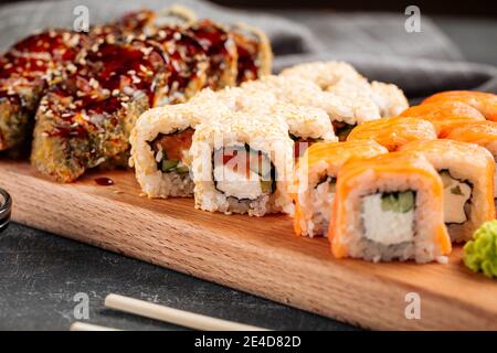 Nahaufnahme von verschiedenen Sushi-Rollen auf einem Holzbrett Stockfoto