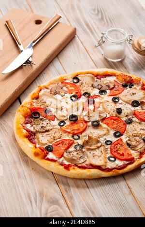 Nahaufnahme Hühnerpizza mit Pilzen und Oliven Stockfoto