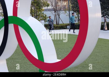 Menschen laufen im Garten des Japanischen Olympischen Museums mit einem Teil des Olympic Rings-Denkmals im Vordergrund. (Januar 2021) Stockfoto