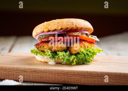 Nahaufnahme auf Zinger Burger mit frittiertem Huhn auf dem Holztisch Stockfoto