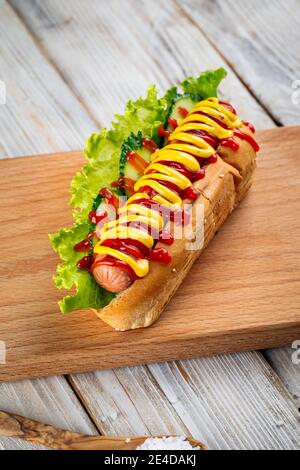 Hot Dog mit Senf und Ketchup auf Holzbrett Stockfoto