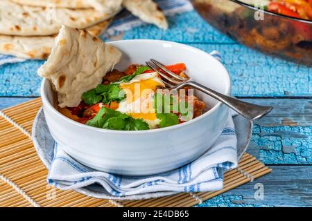 Shakshuka - klassisches nordafrikanisches und nahöstliches Gericht Pochierte Eier in gewürzter Tomaten- und Pfeffersauce Stockfoto