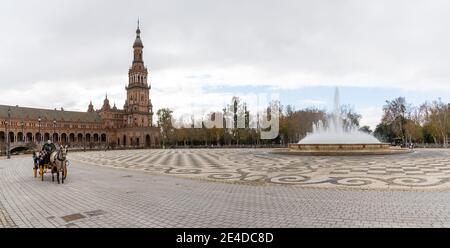 Sevilla, Spanien - 10. Januar 2021: Kutscher mit Pferd und Buggy und Gesichtsmaske wartet auf Touristen an einem leeren Plaza de Espana während der Coronavirus-Zeiten Stockfoto