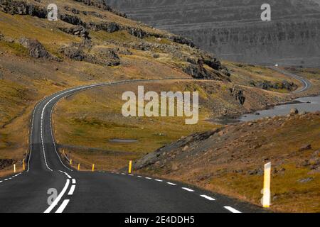 Eine lange Straße, die durch große Berge führt. Islandstraße 1 führt durch die östlichen Fjorde. Stockfoto