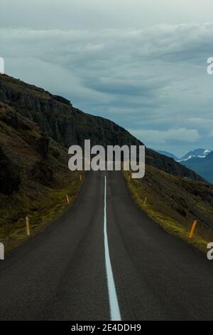 Eine lange Straße, die durch große Berge führt. Islandstraße 1 Stockfoto