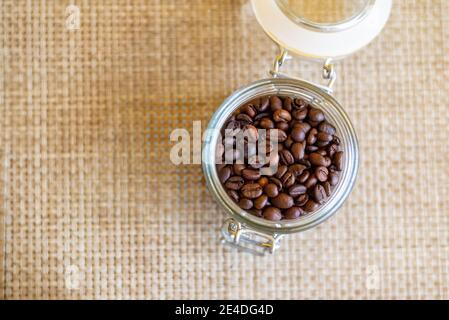 Geröstete Kaffeebohnen in einer transparenten Flasche auf dem Tisch Stockfoto