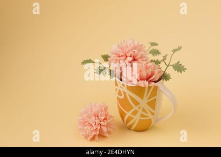 Minimales Konzept einer kleinen Bouqet aus rosa Blumen und Blättern in der Tasse. Vintage Frühjahrskonzept. Beigefarbener Hintergrund in Pastelltönen Retro-Mode-Ästhetik. Stockfoto