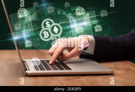 Business Hand arbeiten an der Börse mit Kryptowährungen Symbole kommen Aus dem Laptop-Bildschirm Stockfoto