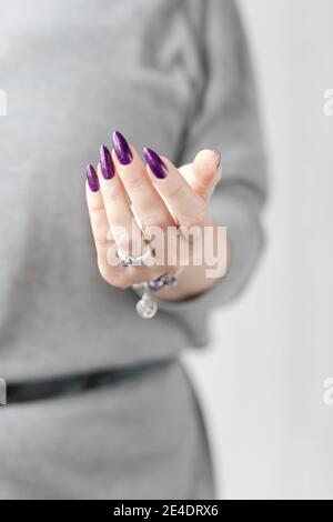 Womans Hände mit langen Nägeln mit violett lila Nagellack Stockfoto