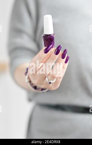 Womans Hände mit langen Nägeln mit violett lila Nagellack Stockfoto