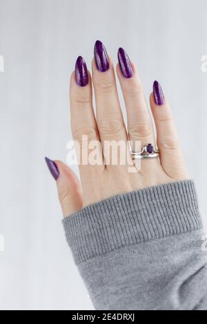 Womans Hände mit langen Nägeln mit violett lila Nagellack Stockfoto