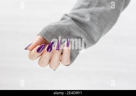 Womans Hände mit langen Nägeln mit violett lila Nagellack Stockfoto