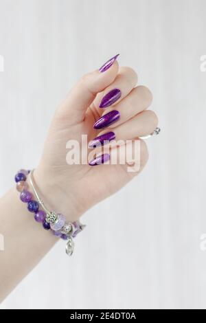 Womans Hände mit langen Nägeln mit violett lila Nagellack Stockfoto