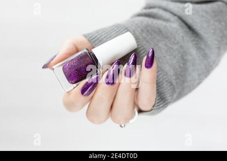 Womans Hände mit langen Nägeln mit violett lila Nagellack Stockfoto