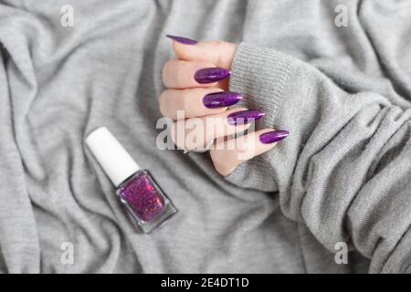 Womans Hände mit langen Nägeln mit violett lila Nagellack Stockfoto