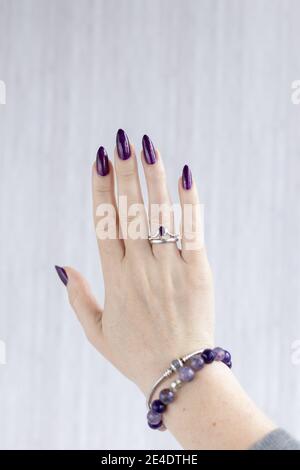 Womans Hände mit langen Nägeln mit violett lila Nagellack Stockfoto