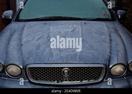 Ein dicker, gemusterter Frost an Windschutzscheibe und Motorhaube eines blauen Jaguar X-Type. Stockfoto