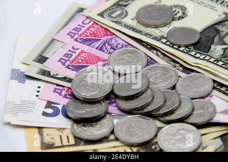 Ukrainisches Geld und amerikanische Dollar auf hellem Hintergrund. Banknoten und Metallmünzen zusammen Stockfoto