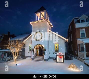 Kleine weiße Kirche mit Weihnachtslichtern und nächtlichem Schnee, Pennsylvania, USA Stockfoto