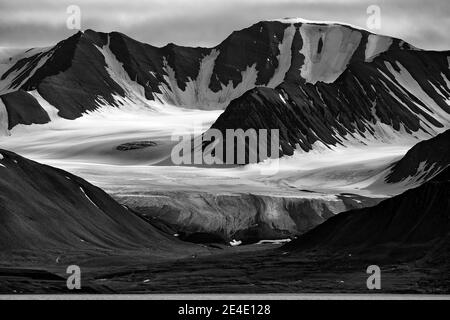 Weißer Gletscher im Berg. Dunkler Himmel mit Wolken. Schwarzweiß-Foto. Land des Eises, Winter in der Arktis. Weißer schneebedeckter Berg, blauer Gletscher in Svalb Stockfoto