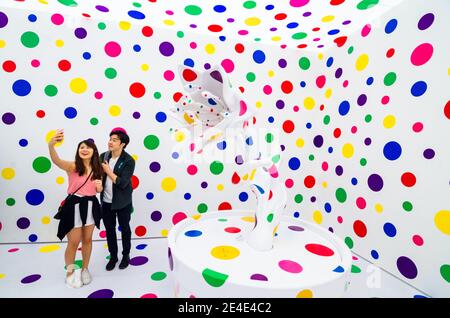 Besucher betrachten die Kunstinstallation des zeitgenössischen japanischen Künstlers Yayoi Kusama in der Gropius Bau Gallery. Weißer Raum mit bunten Punkten. Stockfoto