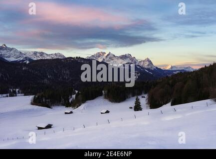 Schöner Sonnenaufgang in den Bergen mit schneebedeckten Hütten Vordergrund - Alpen mit Alpspitze und Zugspitze im Hintergrund Stockfoto