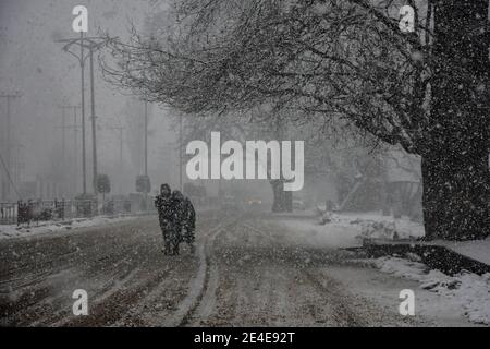 Pendler gehen entlang einer schneebedeckten Straße während Schneefall in Srinagar. Viele Teile Kaschmirs, einschließlich Srinagar, erhielten frischen Schneefall am Samstag. Der Wettermann hat mehr Schnee in den nächsten 24 Stunden vorhergesagt. Stockfoto