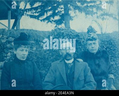 Amerikanisches Archiv Cyanotypisches Porträt eines Mannes mit Schnurrbart und zwei Frauen, die draußen mit Hüten und Mänteln sitzen. Aufgenommen im späten 19. Jahrhundert in Port Byron, NY, USA Stockfoto