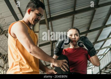 Frau trägt Boxhandschuhe mit ihrem Trainer auf dem stehen Boxring Stockfoto