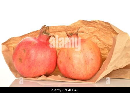 Zwei saftige reife Granatäpfel in einem Papierbeutel, Nahaufnahme, isoliert auf weißem Hintergrund. Stockfoto