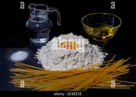 Alle Zutaten, um Spaghetti zu bekommen. Mehl, Ei, Wasser, Olivenöl und Salz, notwendig, um Spaghetti zu machen. Stockfoto
