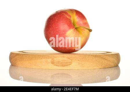 Ein ganzer, roter organischer reifer saftiger süßer Apfel, der auf einem runden braunen Holzständer auf weißem Grund liegt. Stockfoto