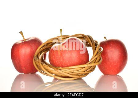 Drei ganze rote leckere reife saftige Äpfel, mit einem Weidenring aus einer Rebe, auf weißem Hintergrund. Stockfoto