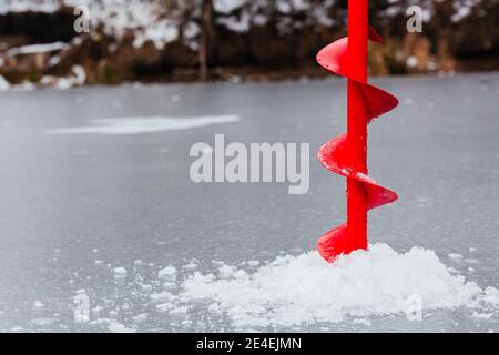 Bohren mit Eisschraube. Eisschnecken zum Angeln. Eisfischen auf dem Fluss. Angeln im Winter. Hintergrund. Eisstruktur Stockfoto