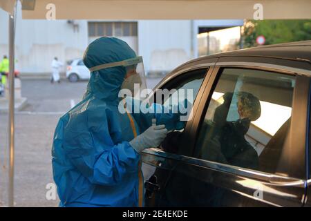 Arzt mit Maske und Visier macht Tampon zu Person im Auto für den Notfall covid-19 sitzen. Stockfoto