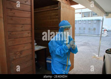 Arzt mit Maske und Visier macht Tampon zu Person im Auto für den Notfall covid-19 sitzen. Stockfoto