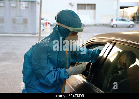 Arzt mit Maske und Visier macht Tampon zu Person im Auto für den Notfall covid-19 sitzen. Stockfoto