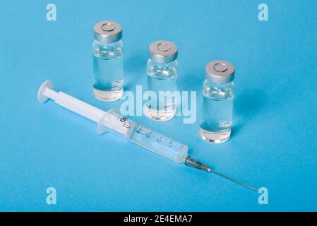 Glasfläschchen mit Covid-19-Impfstoff und Einwegspritze auf blauem Hintergrund. Coronavirus-Impfstoff. Behandlung von Krankheiten und Infektionen. Impfung Stockfoto