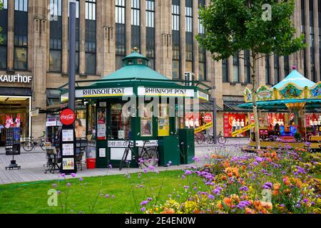 Zeitungskiosk und Vintage-Karussell vor dem Kaufhof an der Königsallee an einem schönen Sommertag. Stockfoto