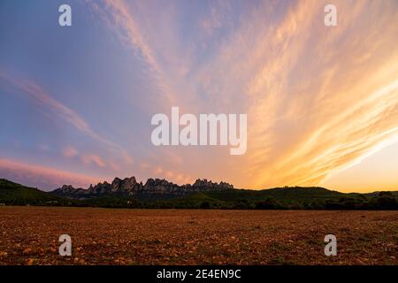 Sonnenuntergang auf dem Berg Montserrat, dem berühmtesten Berg Kataloniens. Wolken am Himmel völlig orange. Stockfoto