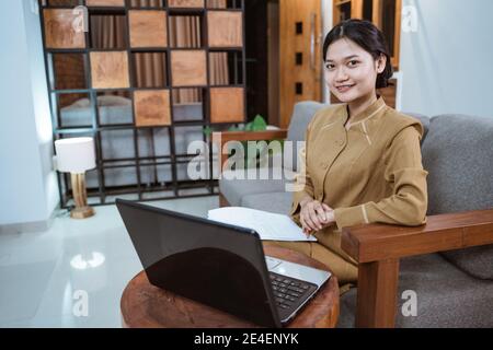 Frau in Regierungsdiener Uniform sitzen auf der Couch während Online-Meetings mit einem Laptop, wenn Sie von zu Hause aus arbeiten Stockfoto