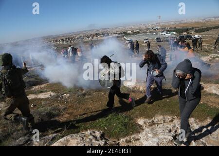 Hebron, Westjordanland von Hebron. Januar 2021. Demonstranten laufen, um sich von Tränengas zu bedecken, das von israelischen Soldaten während eines Protestes gegen die Angriffe israelischer Soldaten und israelischer Siedler auf ihr Land im Dorf Yatta, südlich der Stadt Hebron im Westjordanland, abgefeuert wurde, 23. Januar 2021. Kredit: Mamoun Wazwaz/Xinhua/Alamy Live Nachrichten Stockfoto