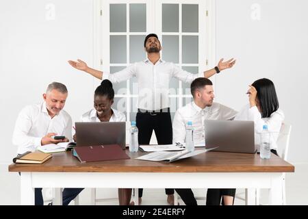 Gruppenbild der erfolgreichen Millennial, indischen männlichen Chef CEO stehen hinter mit erhobenen Händen mit multirassischen Kollegen im Büro, diverse Unternehmen Bus Stockfoto