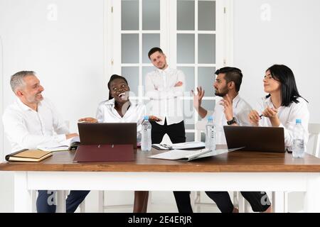 Junge multikulturelle Geschäftsleute diskutieren Geschäftsideen während des Treffens im Büro, verblendter Chef auf dem Hintergrund Stockfoto