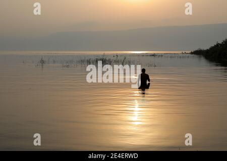 Mann Silhouette betritt Galiläa See in Israel bei Sonnenaufgang. Stockfoto