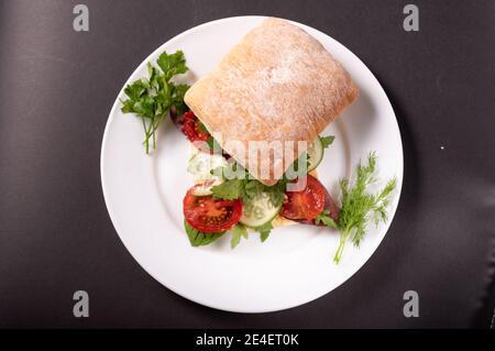 Burger Brötchen Sandwich mit Gemüse. Sandwich auf einem weißen Teller. Stockfoto
