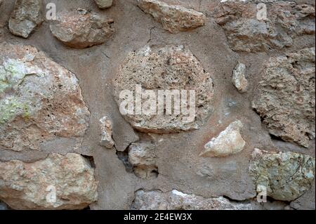 Detail eines alten und verfallenen Mauerstückes mit Steinen und Mörtel. Stockfoto