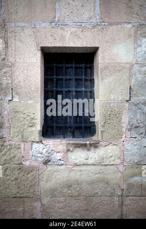 Detail eines alten Holzfensters mit Grill in einem Mauerwerk Stockfoto